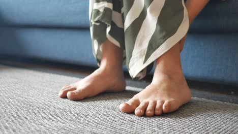 woman sitting on a couch with her feet on the floor