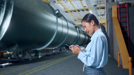 side view of woman not satisfied and shakes her head while using mobile phone in pipe manufacturing factory