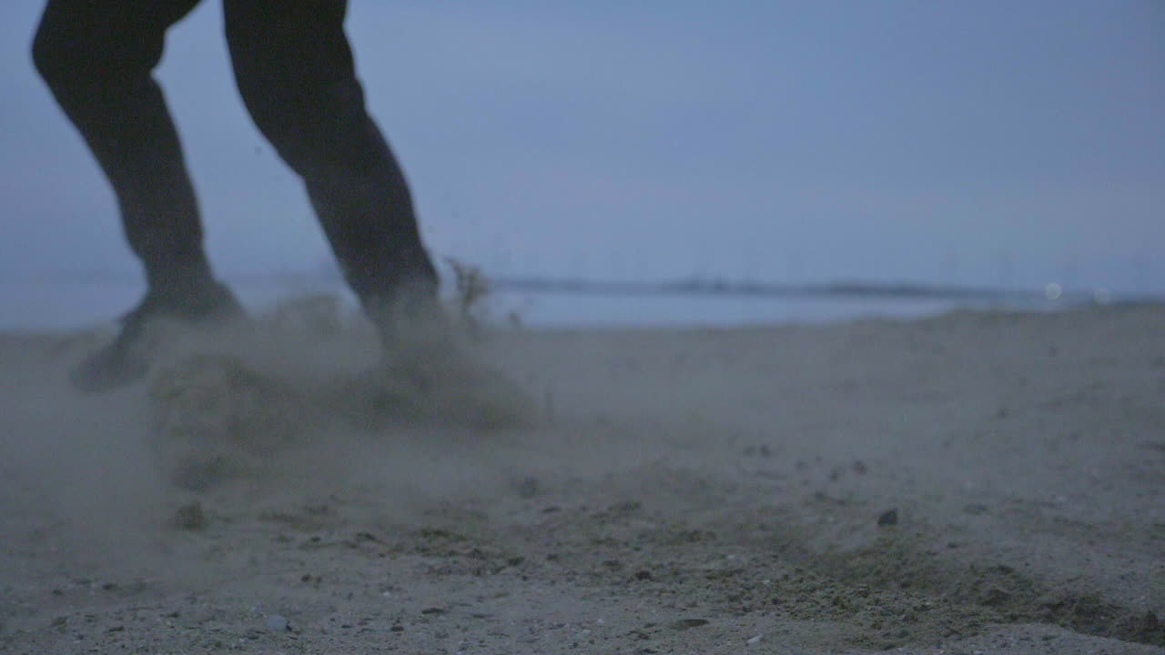 Close up of feet running on sand in slow motion on a cool blue day