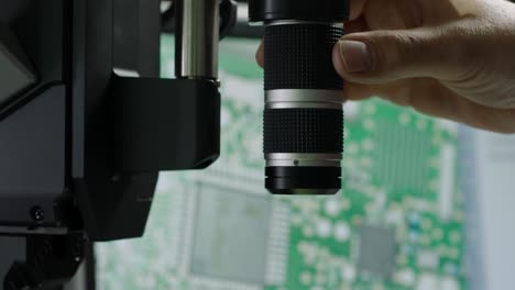 Close-up-of-a-person's-hand-adjusting-a-camera-lens,-technology-theme,-indoors,-selective-focus