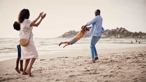 una familia feliz jugando juntos en la playa.
