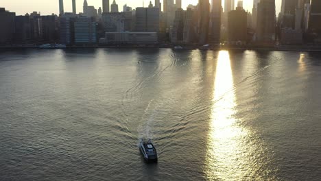 Un-Lento-Y-Dramático-Alejamiento-De-Un-Transbordador-De-Nueva-York;-Luego,-La-Cámara-Se-Inclina-Hacia-Arriba-Para-Revelar-Una-Puesta-De-Sol-Dorada-Y-El-Horizonte-De-La-Ciudad-De-Nueva-York-En-El-Fondo