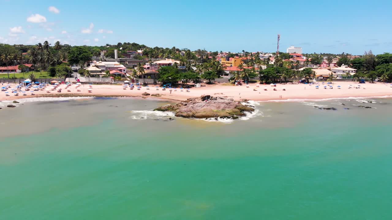 Drone fliyng away from the shore to the open sea showing some people fishing in a top of a big rock
