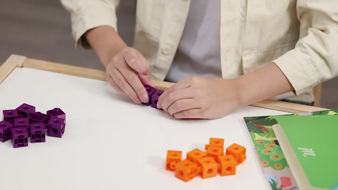 Close-up shot of a child's hands connecting purple plastic blocks during a classroom activity