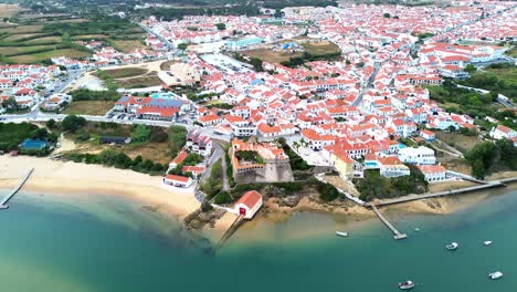 aerial view over small coastal town, blue ocean, red roofs, 4k