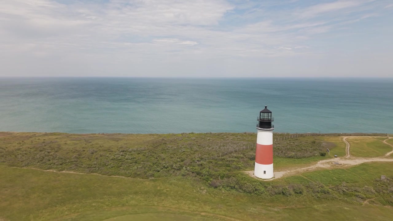 Vedute del faro di Sanity Head con l'Oceano Atlantico sullo sfondo a Nantucket, Massachusetts, in una calda e soleggiata giornata estiva. Ripresa aerea con vedute di vegetazione.