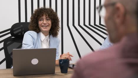 Cheerful businesswoman looking at colleagues during conference meeting