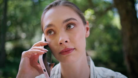 serious woman have phone conversation in park close up. girl talking smartphone