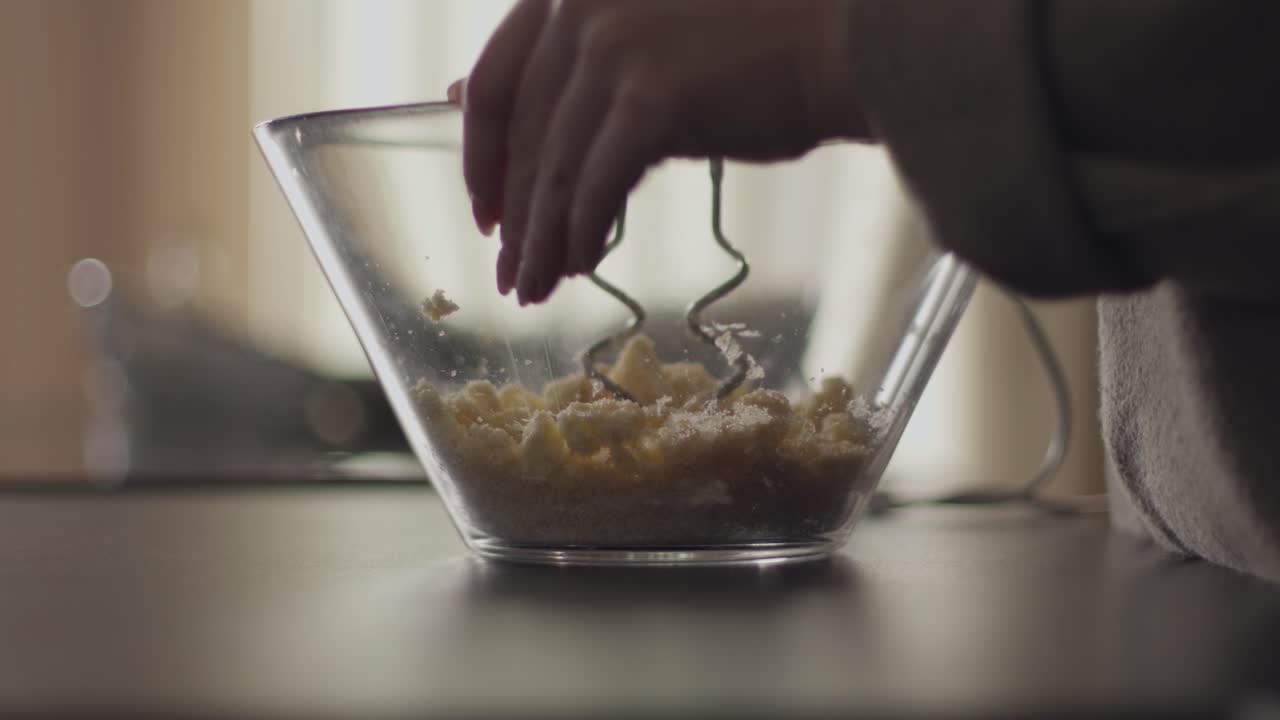 Ingredienti alimentari mescolati a mano in una ciotola di vetro trasparente sul tavolo