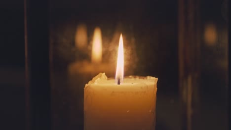 close up of candle flame burning inside glass latern at night