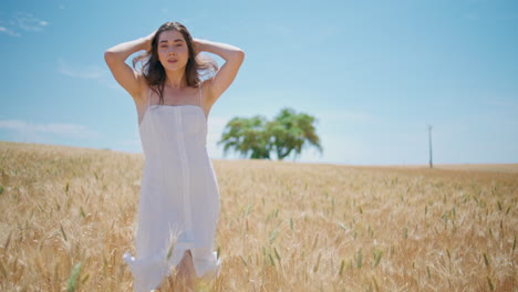 modelo femenino cruzando granos de trigo paisaje de verano. chica sonriente toca el cabello