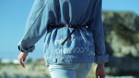 woman walking down the street, wearing blue jeans and denim jacket