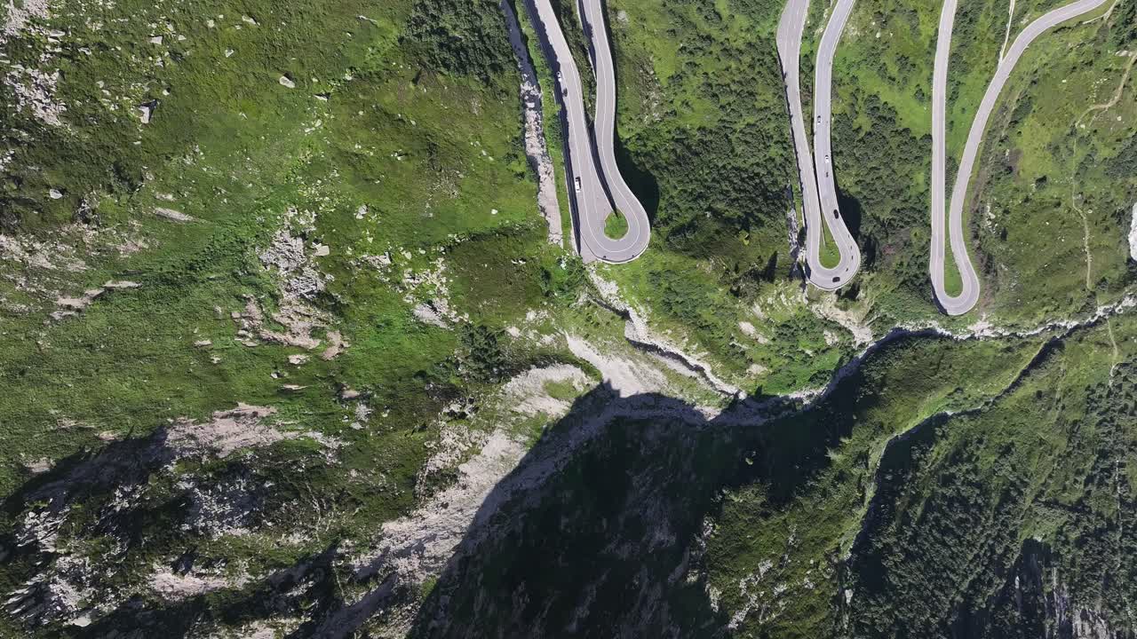 Aerial - serpentine road winding through green alpine landscape of Grimselpass, connecting Bern and Wallis cantons, Switzerland
