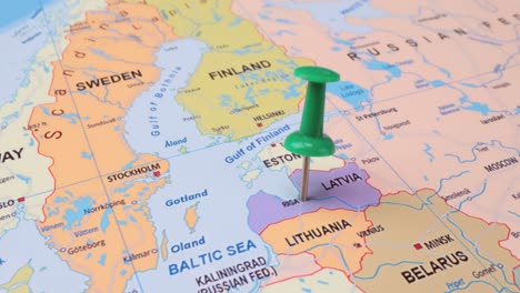 letonia - concepto de viaje con un alfiler verde en el mapa del mundo. el punto de ubicación en el mapa apunta a riga, la capital de letonia.