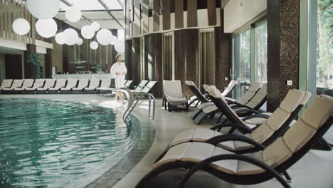 handsome man taking off clothes near water pool at luxury hotel.