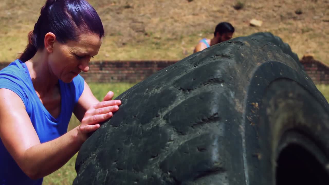 Woman performing workout with tire at boot camp