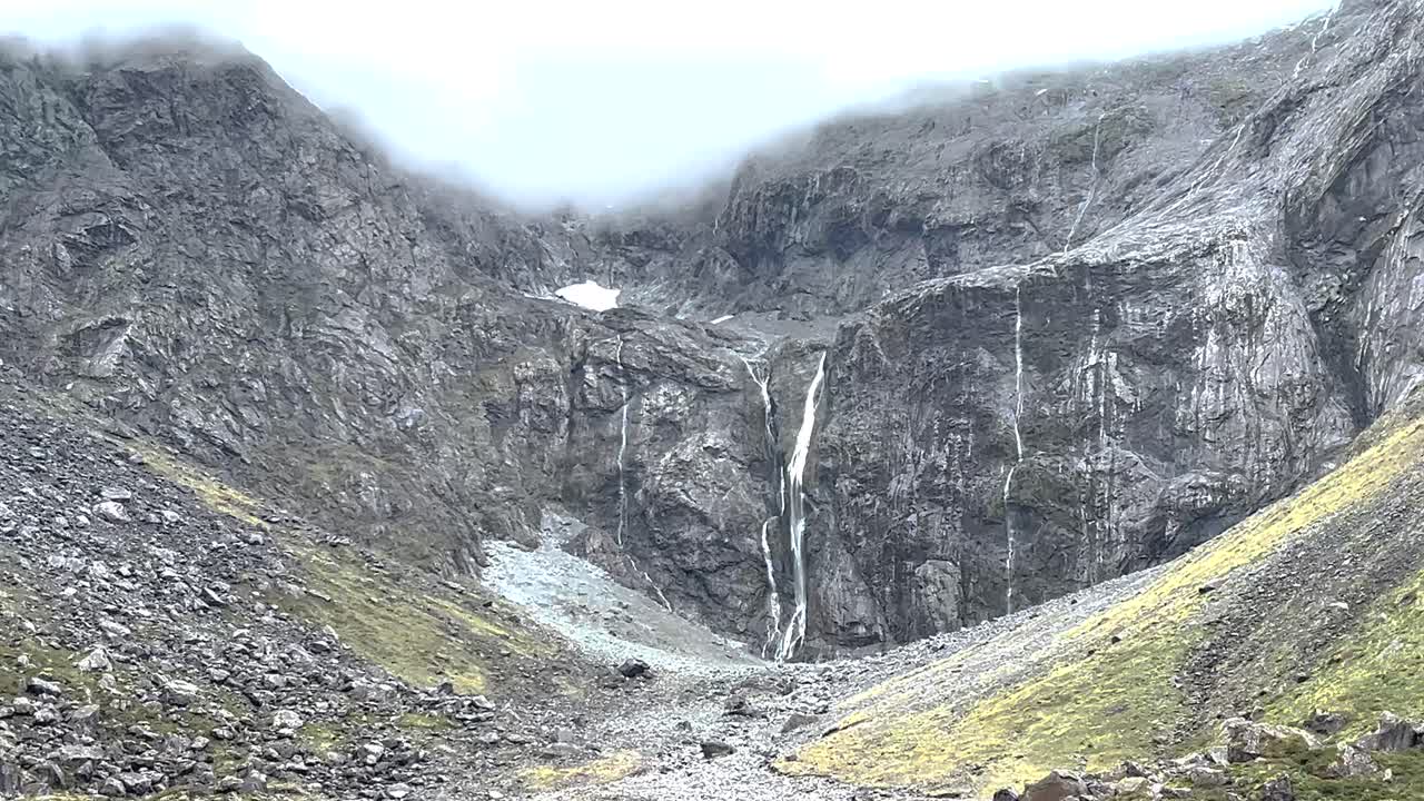 Natura selvaggia con aspre montagne rocciose e cascate, viaggio verso Milford Sound in Nuova Zelanda