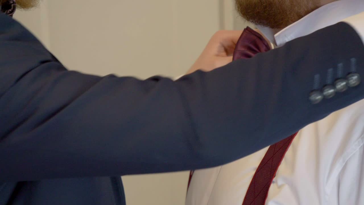 Side View of Best Man Helping Groom with Bow Tie Before Wedding