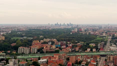 drone moves left, panning down from milan's skyline to a bustling highway below