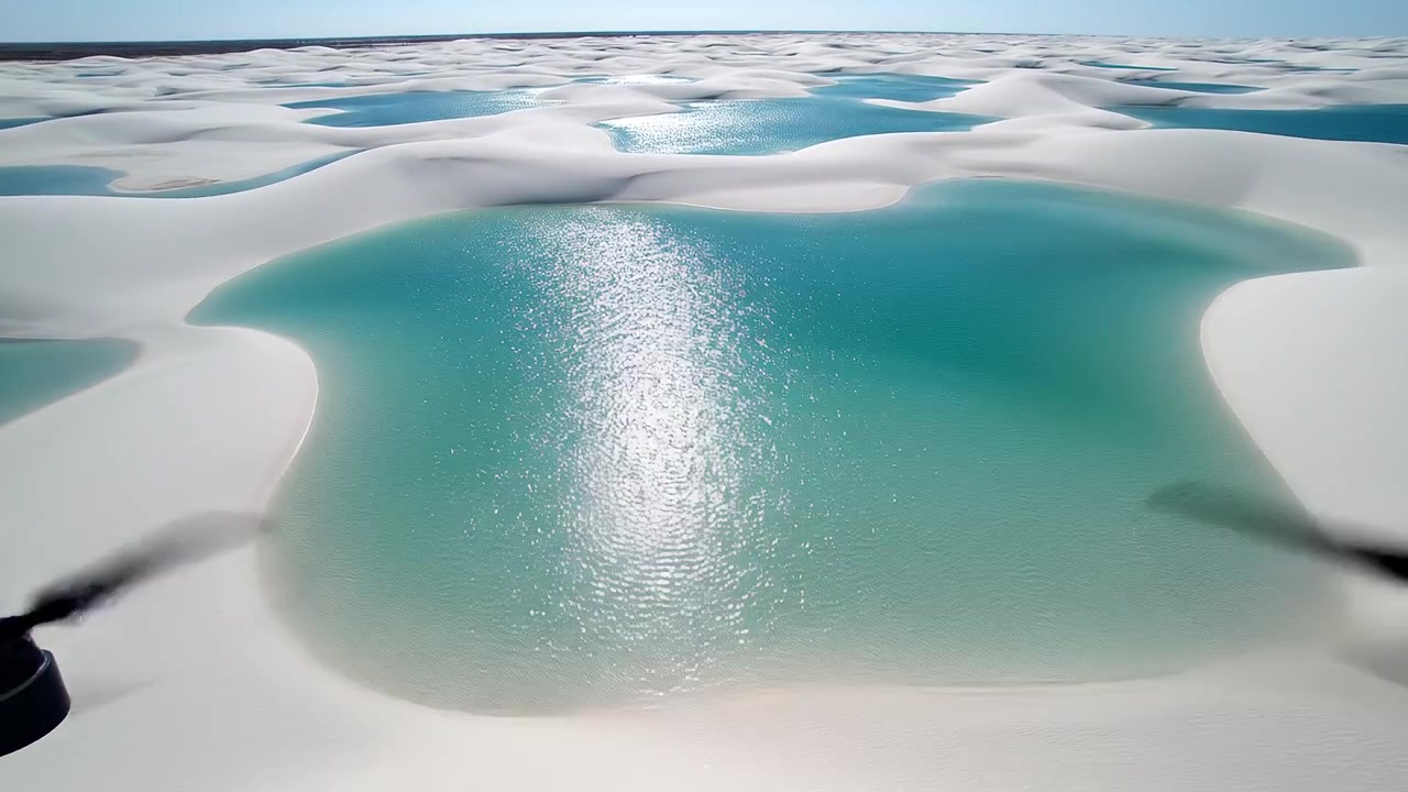 Flyfoto av hvite sanddyner og turkise laguner