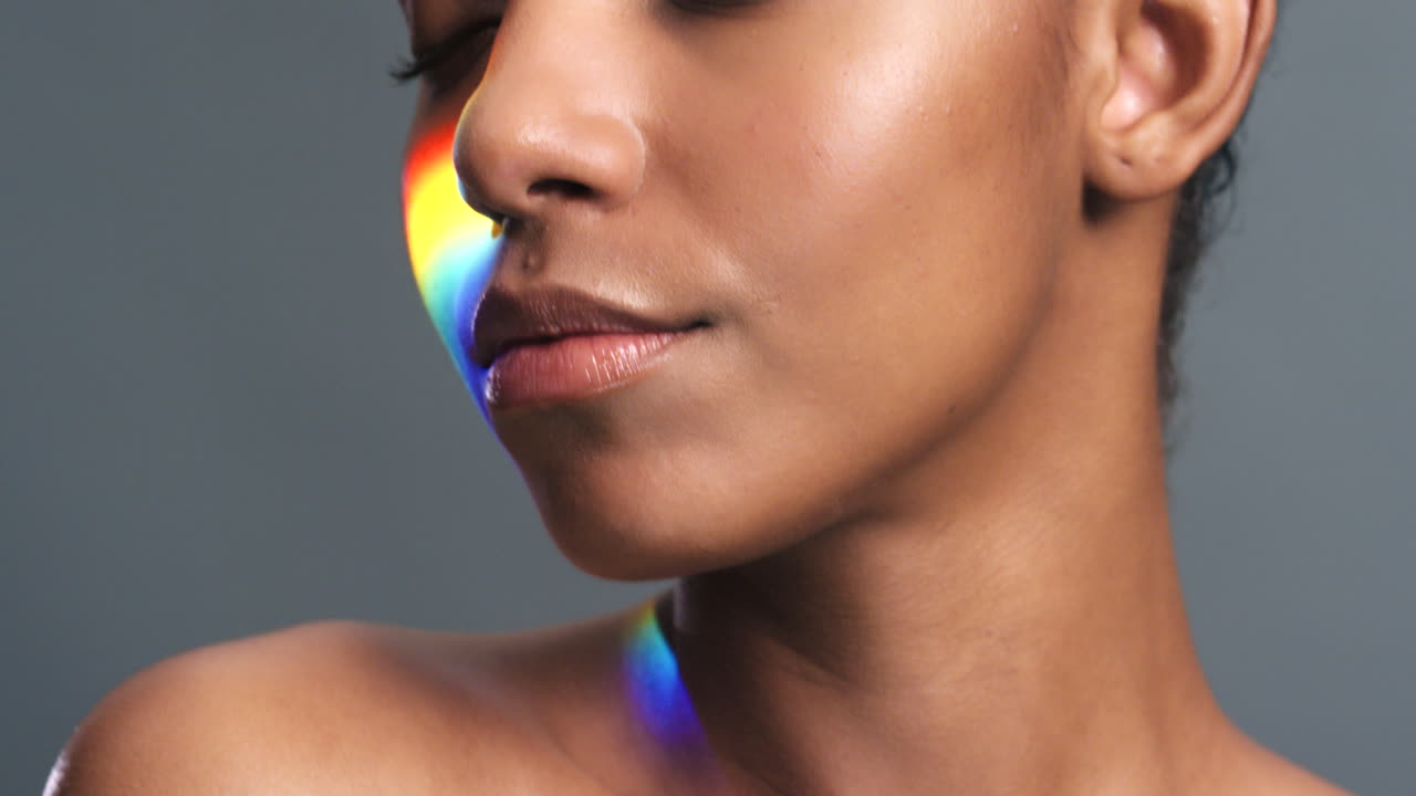 Sorriso di modella con luce arcobaleno sul viso contro