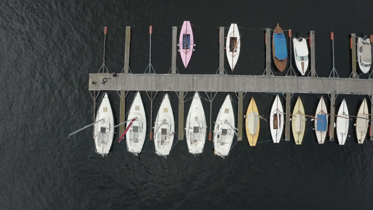Sejlbåde fortøjret i havnen i Arendal, Norge med lang træmole - topdroneoptagelse