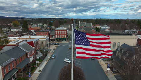 La-Bandera-Estadounidense-Ondea-En-Cámara-Lenta-Sobre-Un-Pequeño-Pueblo-De-Estados-Unidos