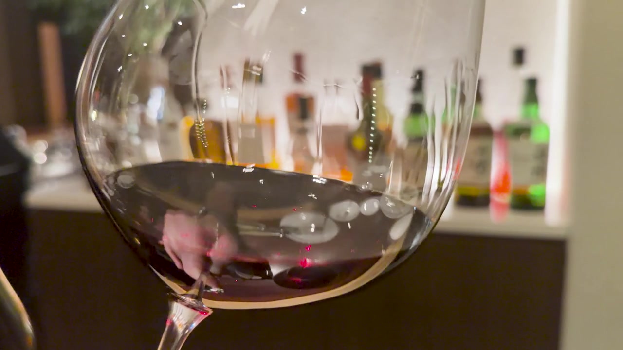 Close-up shot of red wine swirling inside a glass with a blurred bar background
