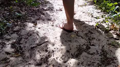 siguiendo los pies de una mujer en la arena de la playa caminando por un bosque en cámara lenta