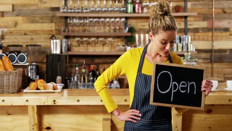 kellnerin zeigt schiefer mit einem offenen schild im café