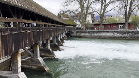 un arroyo que fluye con fuerza bajo un puente de madera