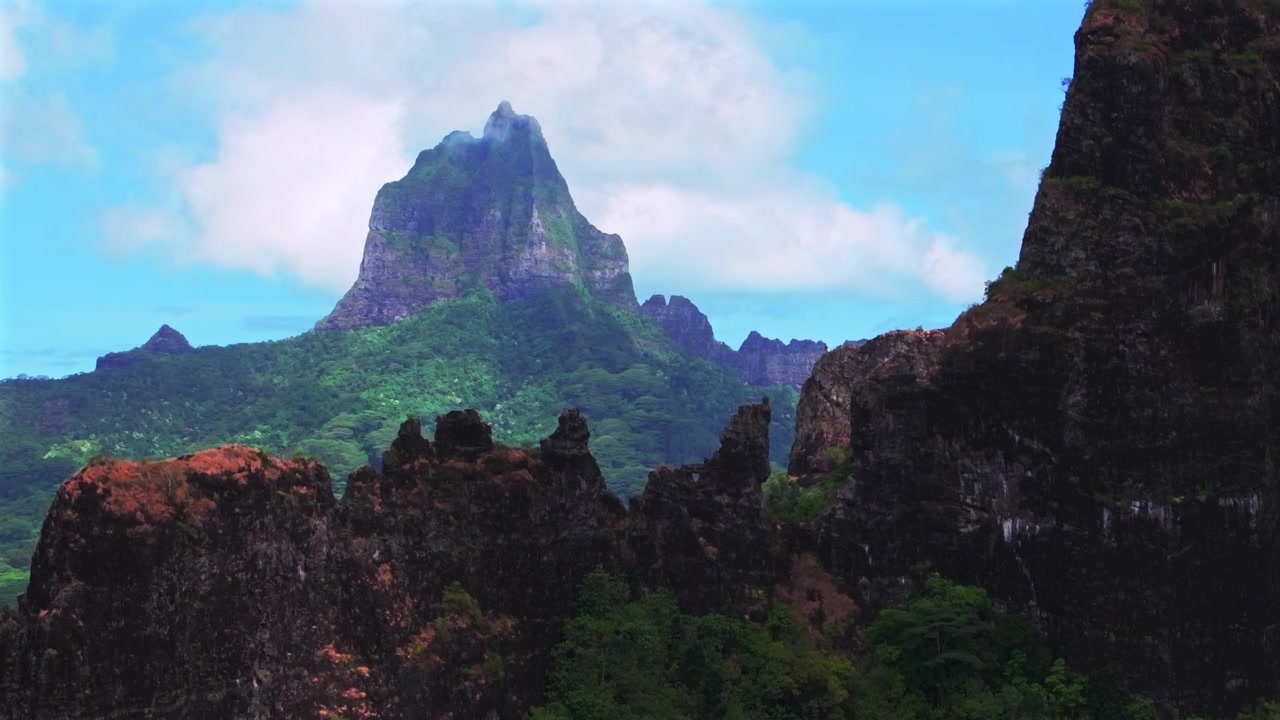 Picos vulcânicos altos e irregulares de Moorea, terreno acidentado, Monte Rotui, Monte Toheia, Polinésia Francesa. Vista aérea de drone do Mirante Belvedere, Baía de Cook e Opunohu, manhã ensolarada, céu azul, nuvens, névoa baixa, revelação ascendente.