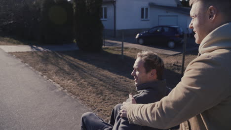 Young-Man-Walking-While-Pushing-His-Disabled-Friend-In-Wheelchair-On-A-Sunny-Day