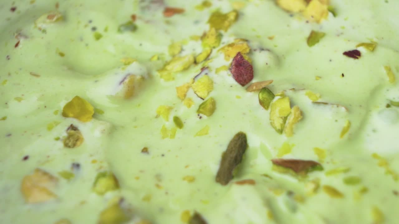 A natural dessert background featuring pistachio ice cream in macro top-down perspective with raw pistachios