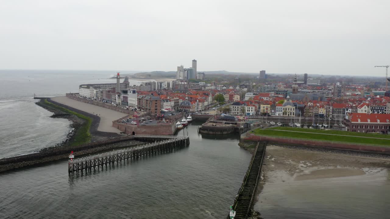 toma aérea hacia atrás de un muelle con edificios frente al mar y una torre y un impresionante panorama de la ciudad de vlissingen, países bajos