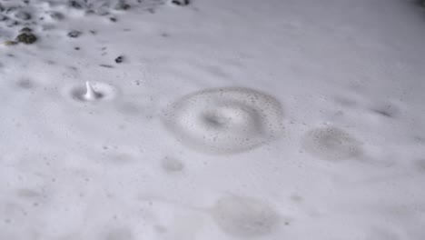 gotas de agua en charco espumoso en el suelo