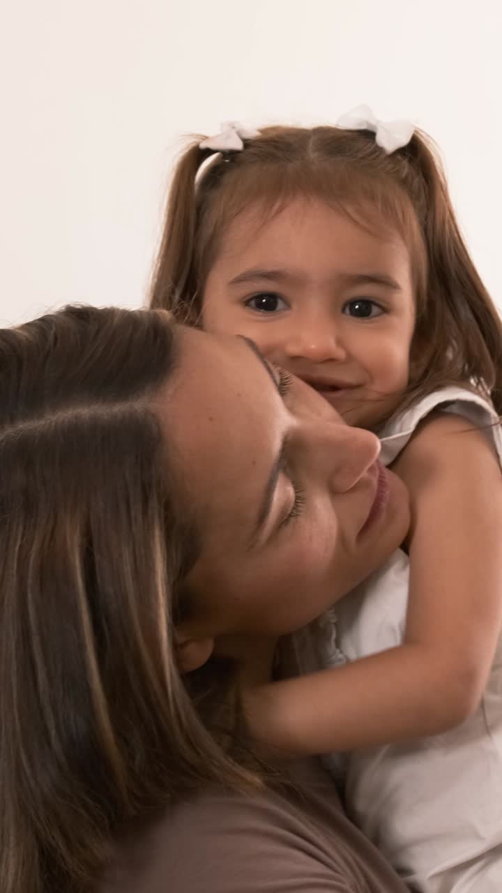 Madre e figlia felici che si abbracciano e si baciano a casa