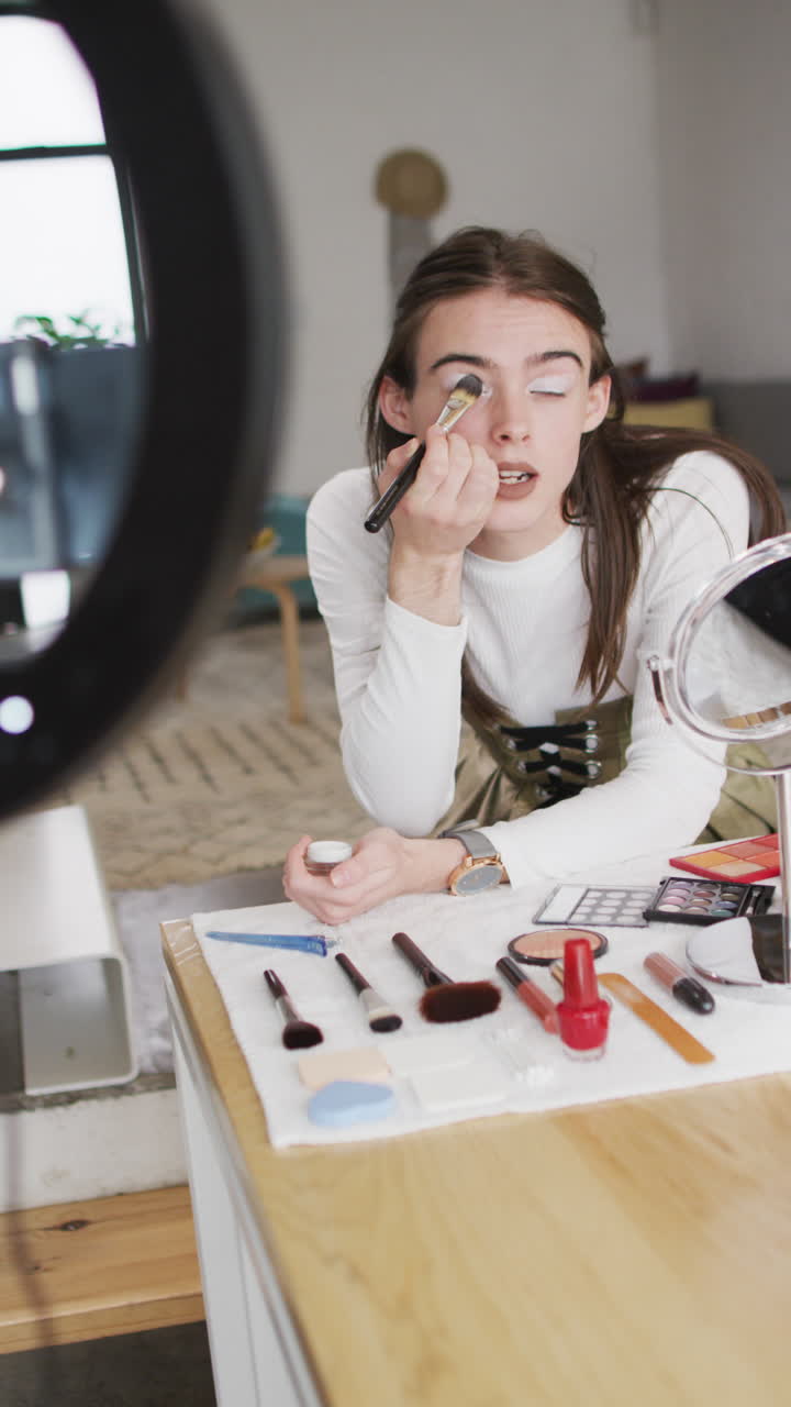 video vertical de una mujer transgénero caucásica no binaria haciendo maquillaje