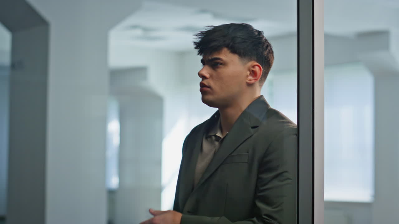 Disappointed manager reading message on smartphone at office with glass walls