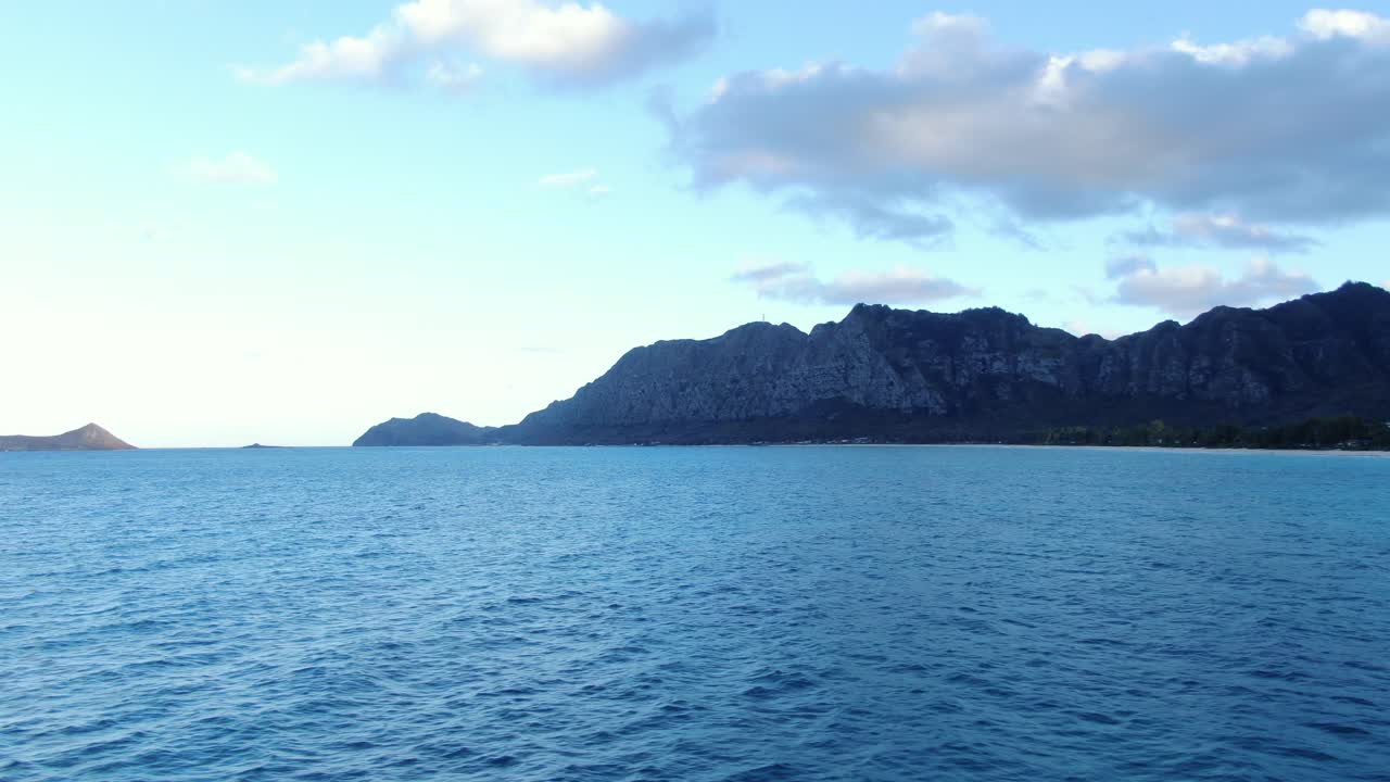 와이마날로 베이의 잔잔한 푸른 바다와 오아후 섬의 셔우드 숲 위로 드론 팬