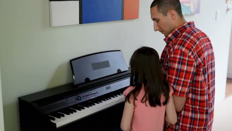 father teaching his daughter to play piano 4k