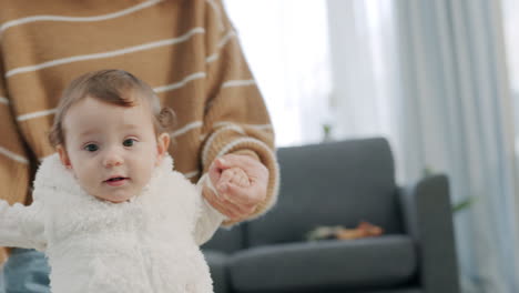 mother help and support baby to walk in house