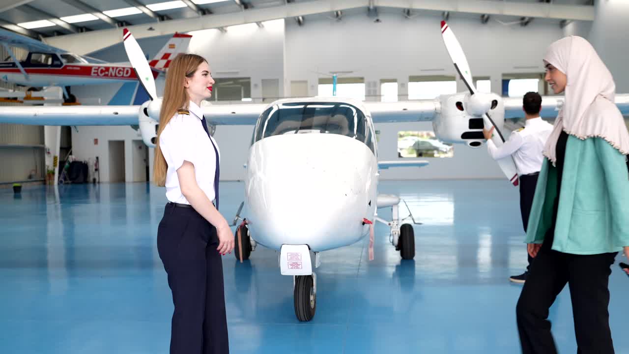 People in an airport hangar with an airplane