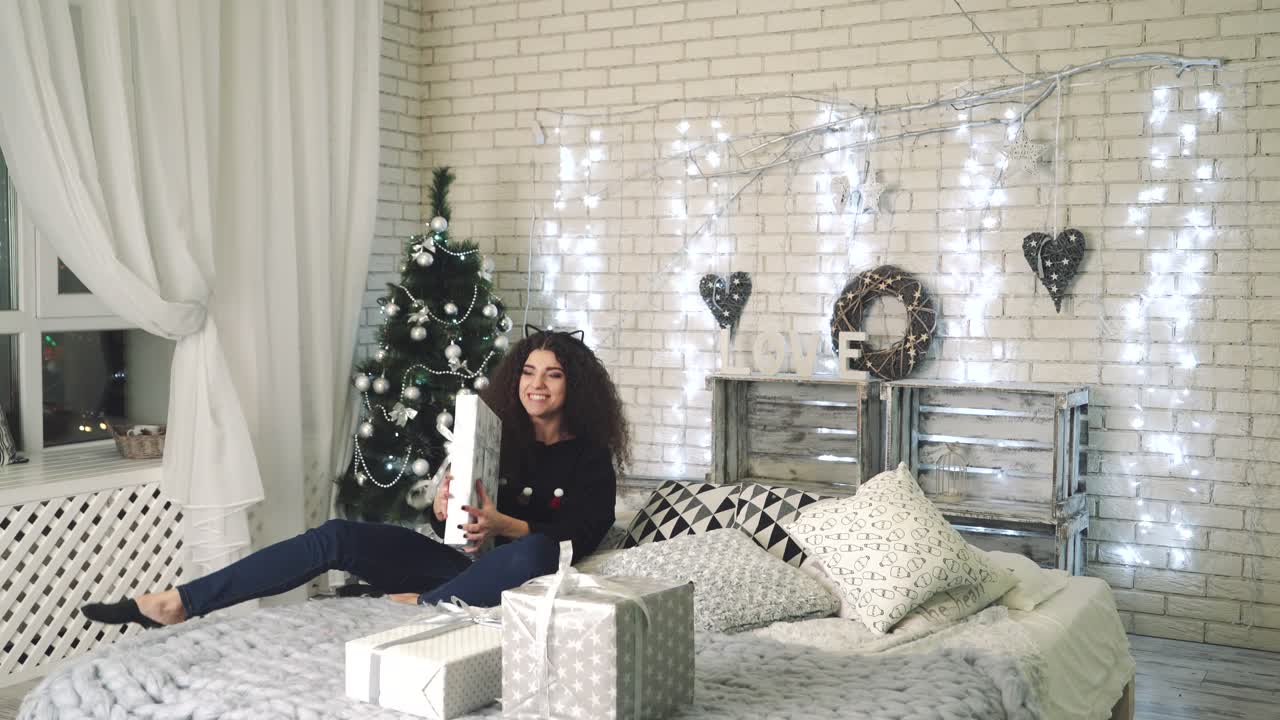 New Year presents concept. Woman opening her New Year gift boxes while lying at home