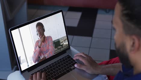 hombre de oriente medio teniendo una videollamada con un colega de oficina masculino en una computadora portátil