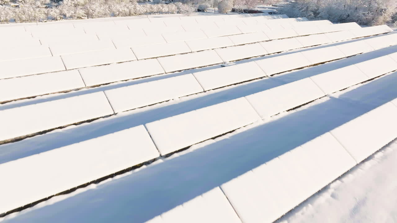 Luftfoto af solbeskinnede, sneklædte solpaneler en solrig vintermorgen