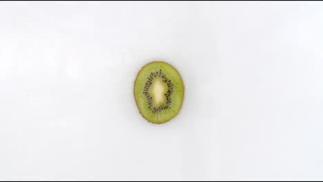 in slow motion water splashes pour water onto one kiwi on a white background. vegetarian and fructorians.