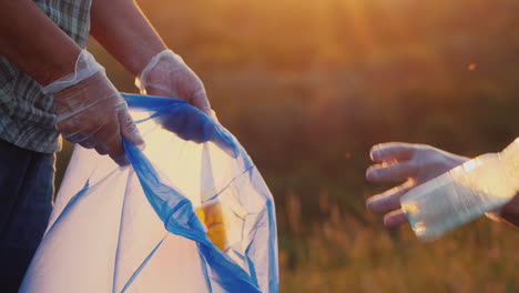 la gente pone basura plástica en la bolsa limpia el primer plano del prado