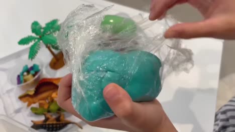 child opening up home made playdough out of a dinosaur themed sensory bin