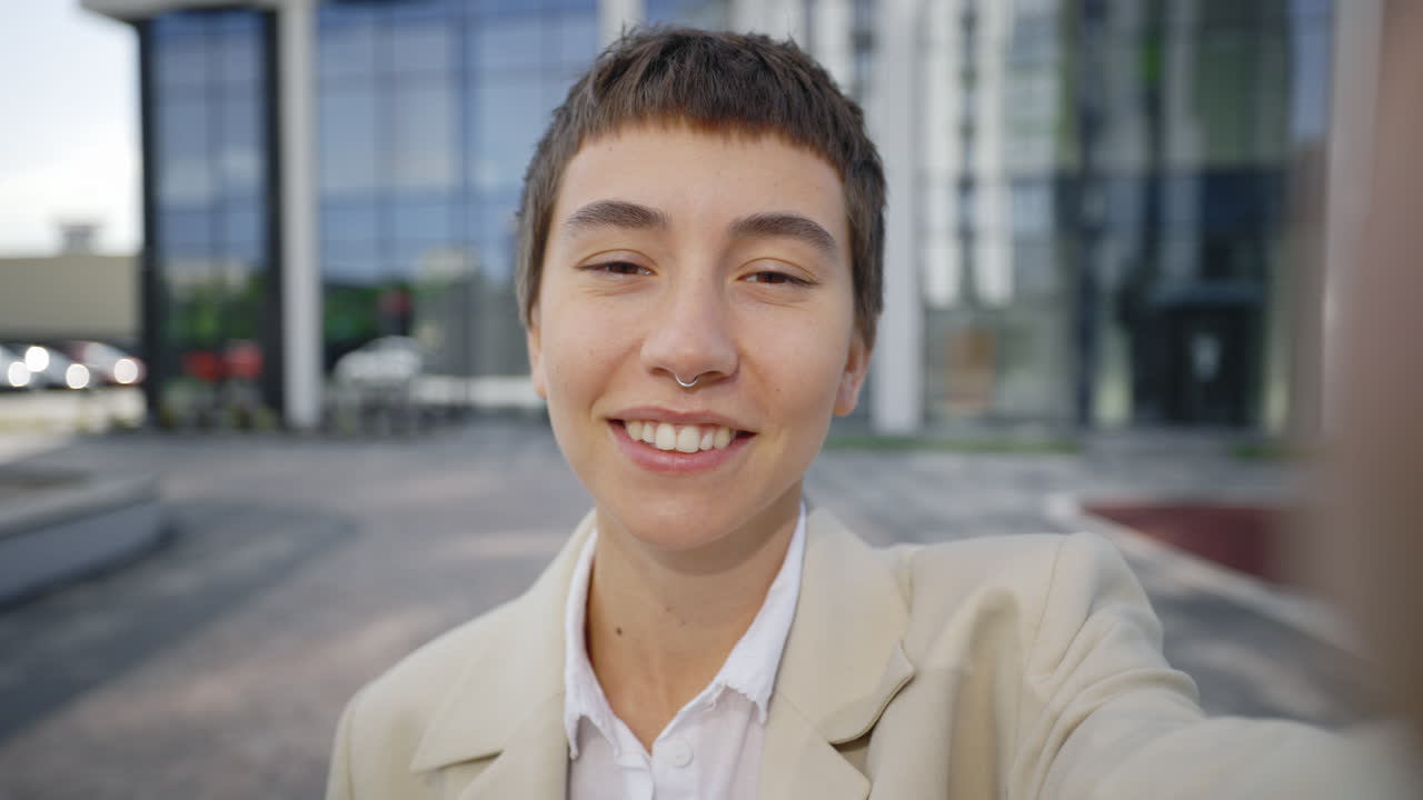 Smiling woman taking a selfie outside office building